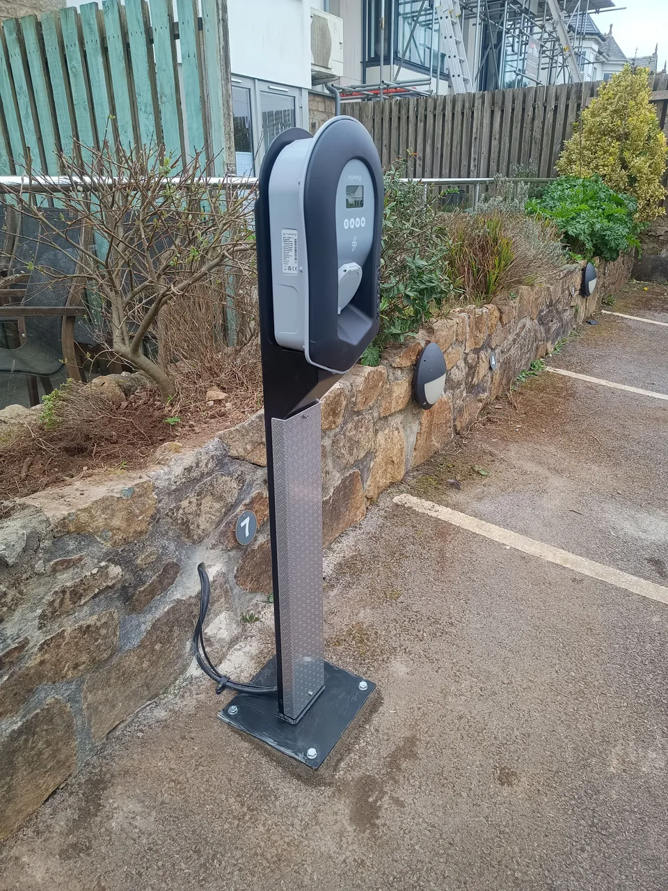 Zappi EV charger on Harvtec’s custom-built pedestal beside parking bays at an apartment building in Carbis Bay