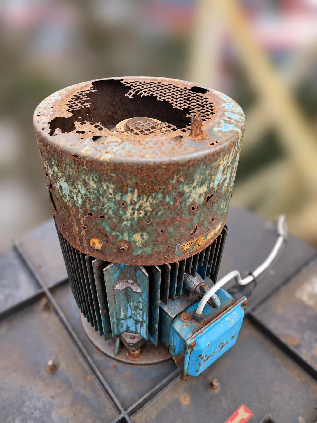 Old extractor motor with extensive corrosion and holes in its cooling-fan cover