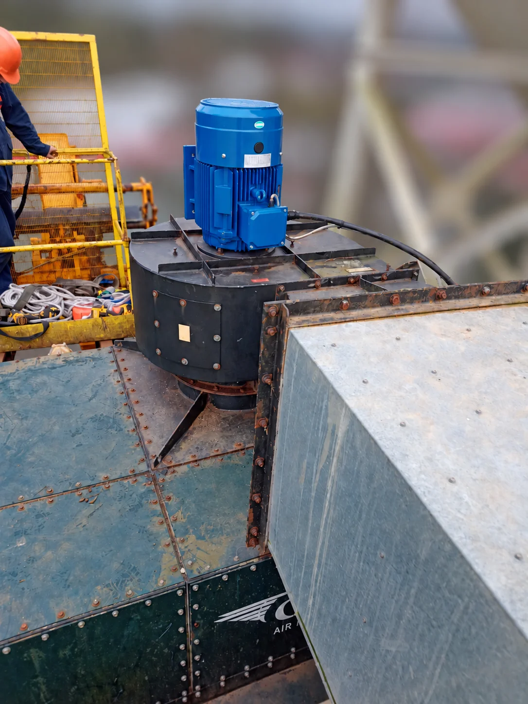 New blue motor installed vertically on the high-level extractor beside an access platform